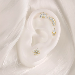 Detailed close-up of four gold S925 silver stud earrings with zircons on a model ear