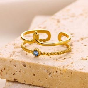 Detailed close-up of a dual-layer gold stainless steel ring with a blue gemstone