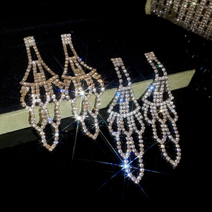 Close-up of dangling rhinestone tassel earrings in gold and silver on velvet