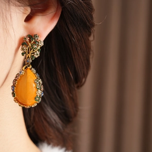 Detail of vintage teardrop earrings with amber stones and colorful crystal inlays