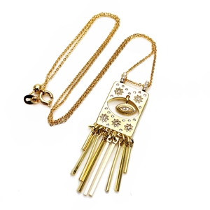 Macro detail of gold evil eye pendant with shimmering cubic zirconia and tassel accents