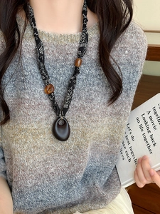Detail of bohemian scarf necklace featuring printed silk, amber beads and oval wood pendant