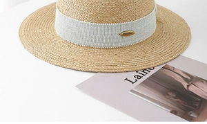 Detail of the boater hat showing fine straw weave and blue ribbon with gold logo