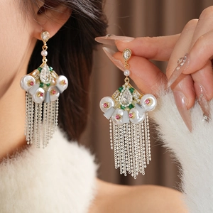Detailed close-up of vintage fan-shaped earrings with pearls and metallic tassels
