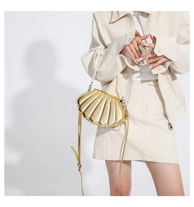 Detail einer goldenen muschelförmigen Handtasche mit Perlen- und Metallketten-Schultergurt