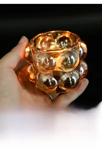 Dettaglio del portacandele in vetro ambrato con texture a bolle e luce calda interna