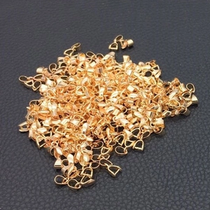 Close-up of golden metal pinch bails for DIY jewelry making on black leather