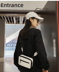 White mini suitcase crossbody bag styled with a black hoodie for a street fashion look