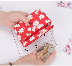 Detail of red daisy coin purse with zipper and metal keychain ring held in hand