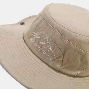 Detail of khaki outdoor bucket hat with embroidered mountain logo and herringbone texture