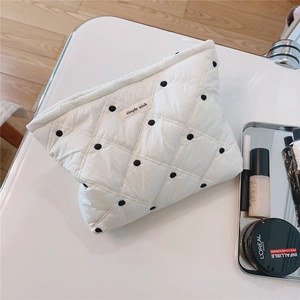 Detailed view of white quilted cotton cosmetic bag with polka dots and black zipper