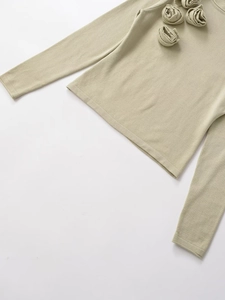 Dettaglio di un maglione in maglia fine con decorazioni floreali 3D fatte a mano sul collo
