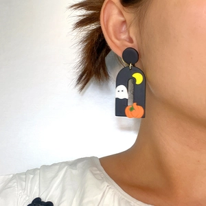 Close-up of black arch Halloween earring featuring white ghosts and orange pumpkins