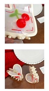 Macro detail of heart-shaped acetate hair claw clips with red cherry patterns