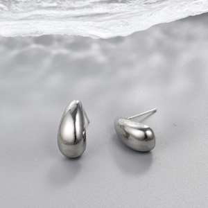 Macro detail of silver teardrop earrings featuring a high-polish mirror finish surface