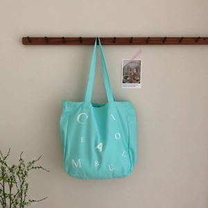 Detail der minzgrünen Canvas-Tasche am Holzhaken mit modischem Buchstabendruck-Design