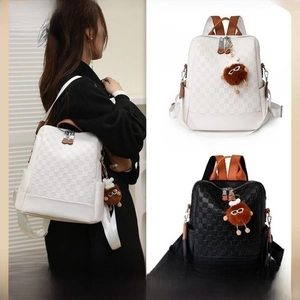 Detail of checkered embossed backpack with zipper closure and brown plush pendant