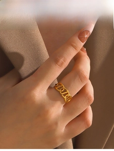 Detail of a polished gold pig nose link ring worn on a finger for a minimalist style