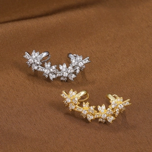 Sparkling flower ear cuff with zircon crystals in gold and silver on silk background