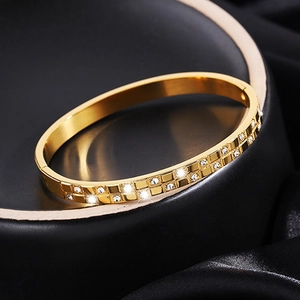 Macro view of gold-plated titanium bangle with pavé-set zircons on black silk