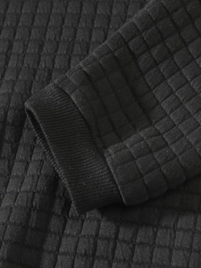 Detail of black waffle knit fabric and ribbed cuff on a men's long sleeve sweatshirt