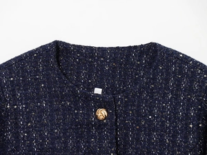 Detailaufnahme des Ausschnitts der marineblauen Tweedjacke mit Goldpailletten und Knopf