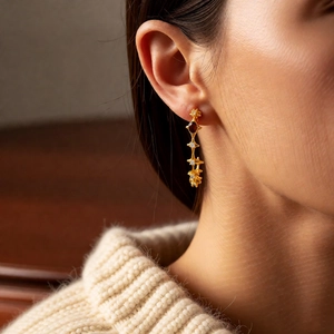 Close-up of 18k gold plated tiger eye stone C-shaped earrings worn by a model