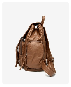 Side view of brown washed leather backpack showing rivet details and tiered side pockets
