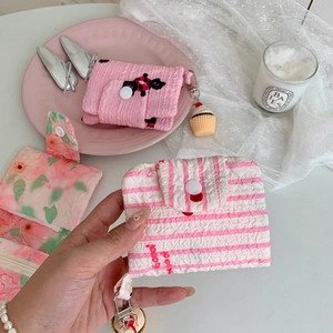 Close-up of floral fabric mini pouch with snap button and cupcake keychain detail