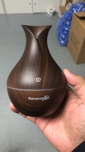 Detail of hand-held ultrasonic humidifier with dark wood grain finish and white brand logo