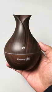 Detail of hand-held ultrasonic humidifier with dark wood grain finish and white brand logo