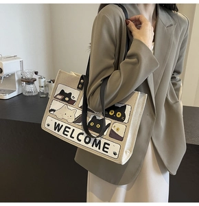 Detail of beige canvas tote bag with black cartoon cat print and dual shoulder straps