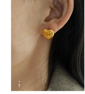 Close-up of model wearing French vintage woven heart stud earrings in a gold finish