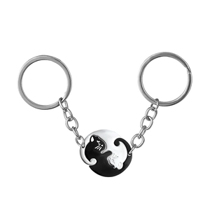 Close-up of black and white interlocking cat pendants with polished metal keychains