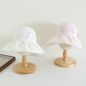 Close-up of girls sun hats with purple floral print and wavy brims on wooden stands