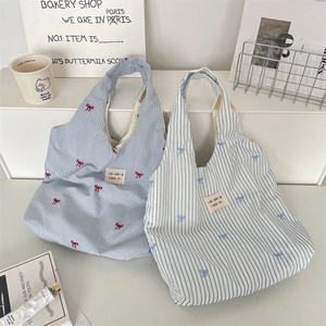 Gros plan de sacs cabas en toile rayée bleue avec broderie nœud et étiquettes tissées