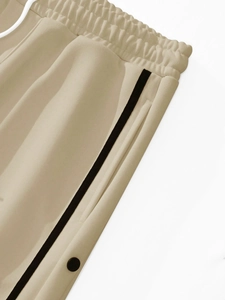 Close-up of elastic waistband with black side stripes and decorative buttons on joggers