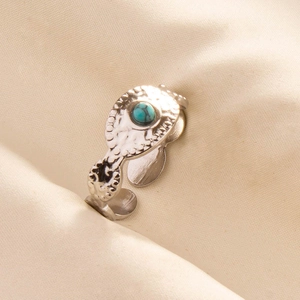 Detail of silver drop-shaped ring with green turquoise stone and engraved patterns