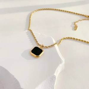 Detail of vintage square black onyx pendant on a golden twisted rope chain necklace