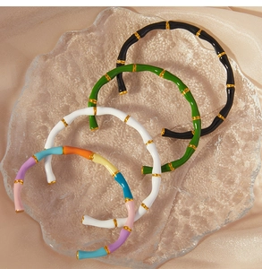 Detailed close-up of colorful enamel bamboo style open bracelets on silk fabric