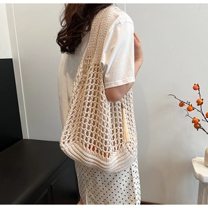 Detail of beige knit tote bag showing hollow mesh pattern and stylish tassel accents