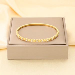 Dettaglio di un bracciale rigido in acciaio placcato oro 18K con zirconi bianchi