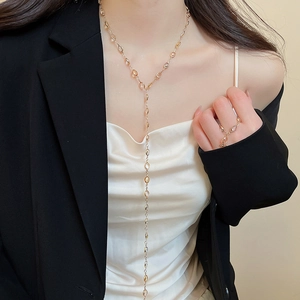 Close-up of golden tassel necklace featuring resin oval accents on a professional model