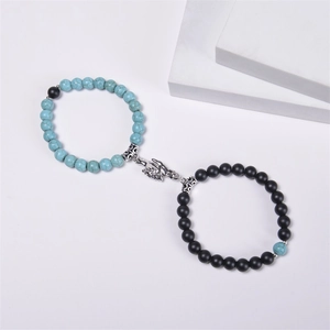 Detail of couple bracelets with blue and black beads and palm-shaped magnetic clasp