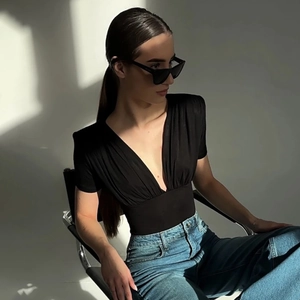Detail of black V-neck bodysuit showing tight fit and pleated texture on short sleeves