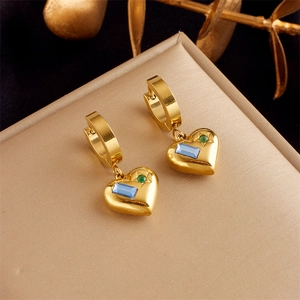 Detail of vintage heart earrings with blue and green gemstones on beige textured box