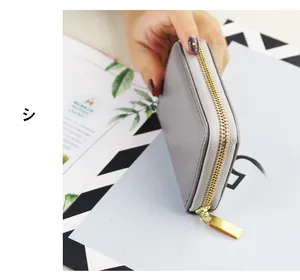 Detailed side view of grey lychee textured faux leather coin purse with gold zipper closure