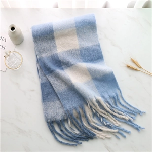 Close-up of soft blue and white checkered scarf with fringe on a marble background