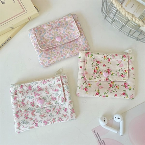Gros plan de trois porte-monnaie en tissu floral avec boutons en cœur et fermetures éclair