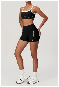 Detailed side view of black high-waisted fitness shorts with white stripe piping trim